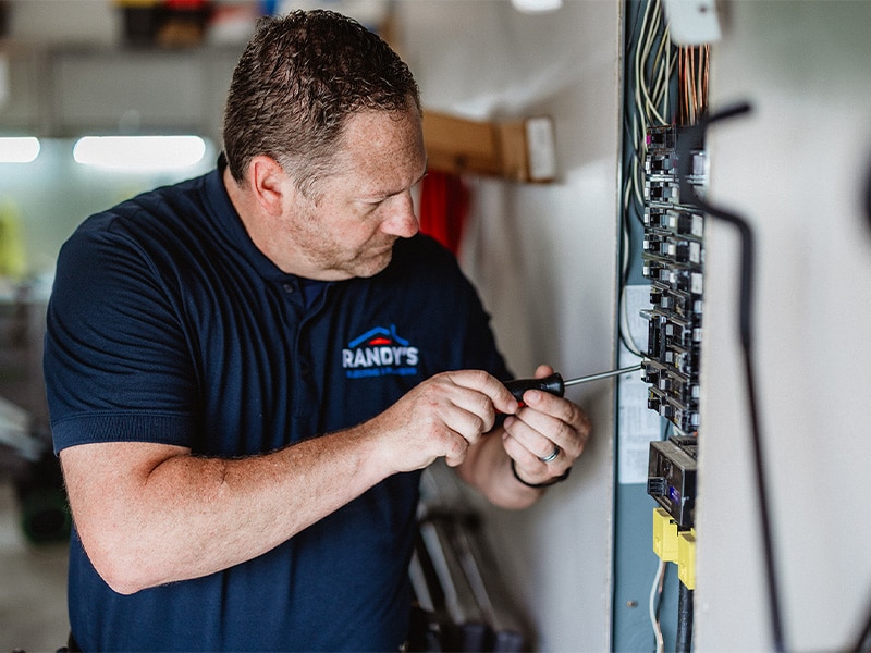 Randy working on electrical panel with screwdriver in hand.