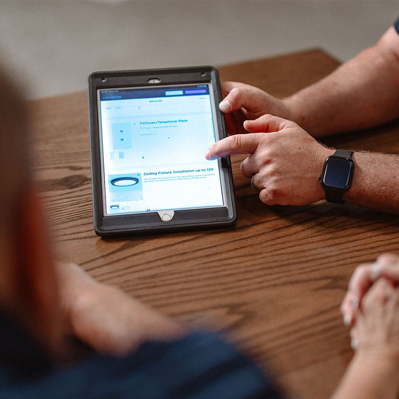Person using a tablet on a wooden table.