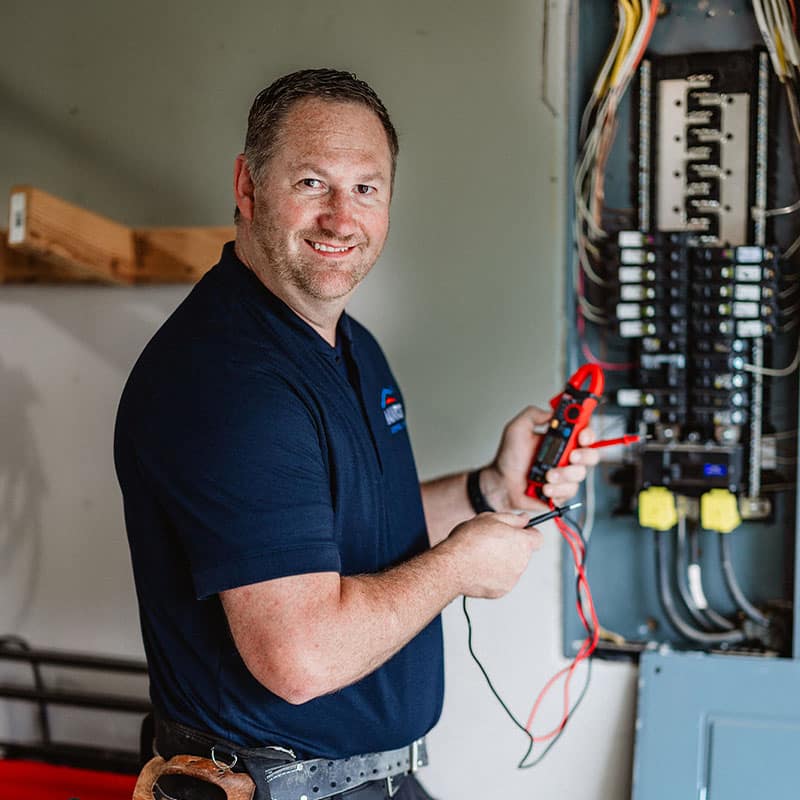 A man using a multimeter to check an electrical panel.