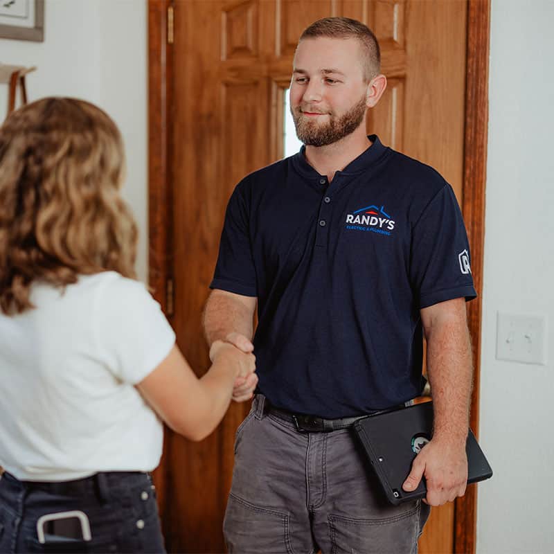 Person in Randy's Electric shirt shakes hands in a doorway.