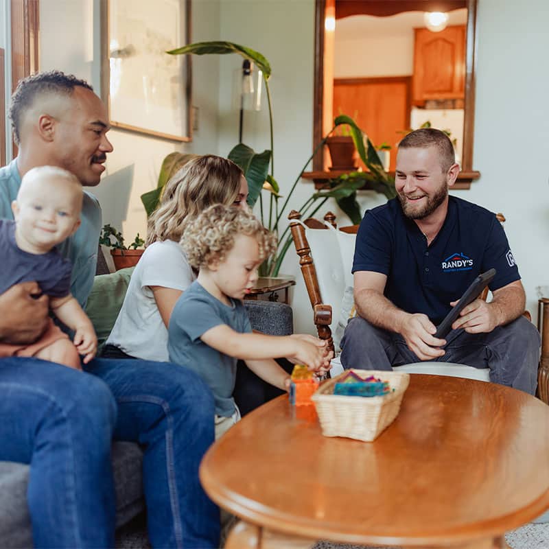 A family sitting on a couch with a professional from Randy's, discussing home services in a living room.