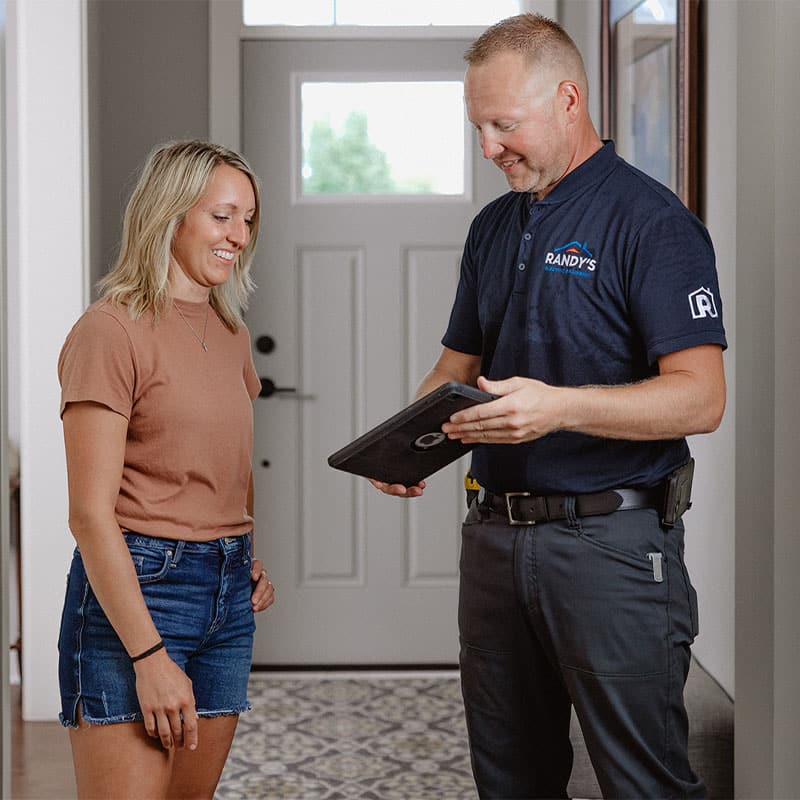 A person discussing home service with Randy's technician using a tablet in a well-lit entryway.