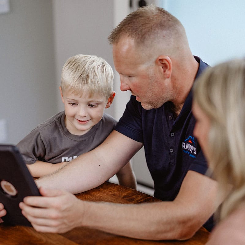 Man and child looking at a tablet together on a wooden table.