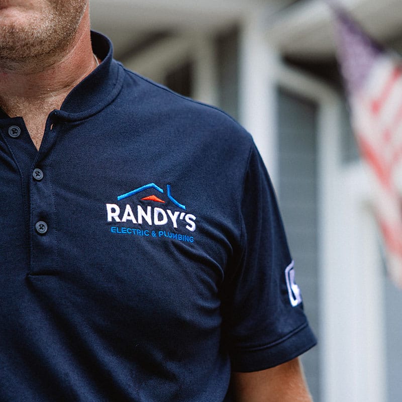 Randy's Electric & Plumbing logo on a blue polo shirt with American flag background.