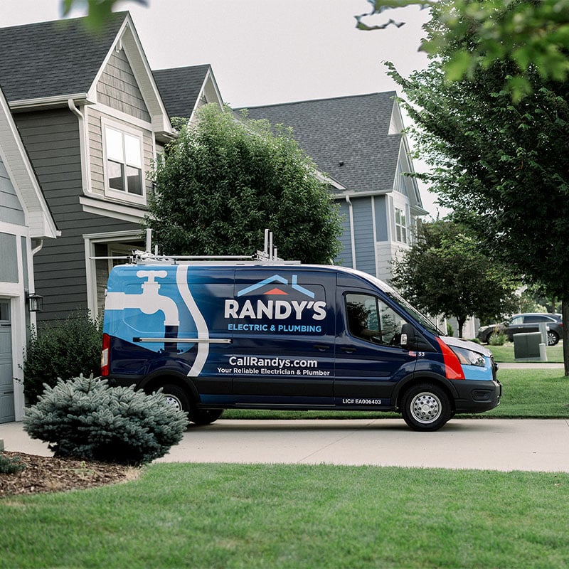 Randy's Electric & Plumbing van parked in front of residential homes, showcasing their services.