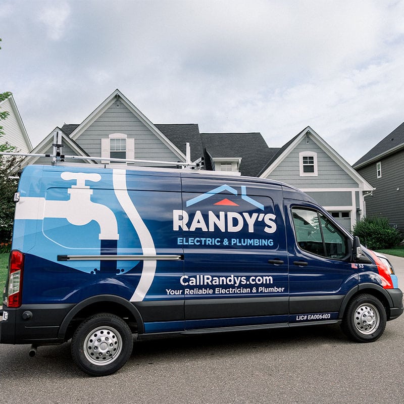 Electric and plumbing service van parked in front of a residential house.