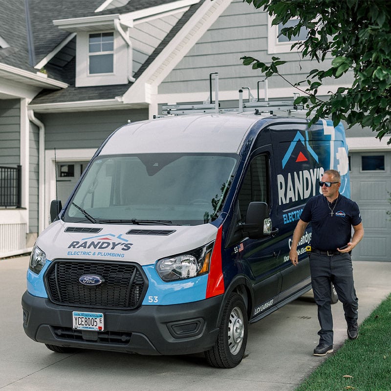 Randy's Electric & Plumbing van with a technician outside a house, ready for service.