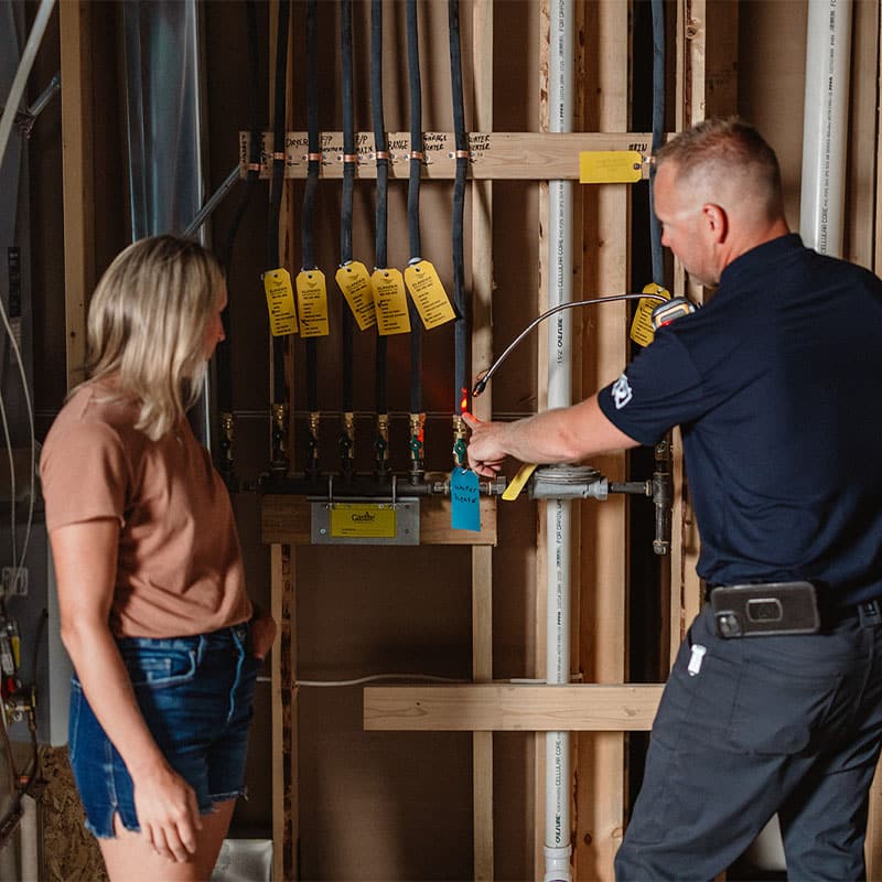 Person inspecting plumbing system with a professional in a construction setting.