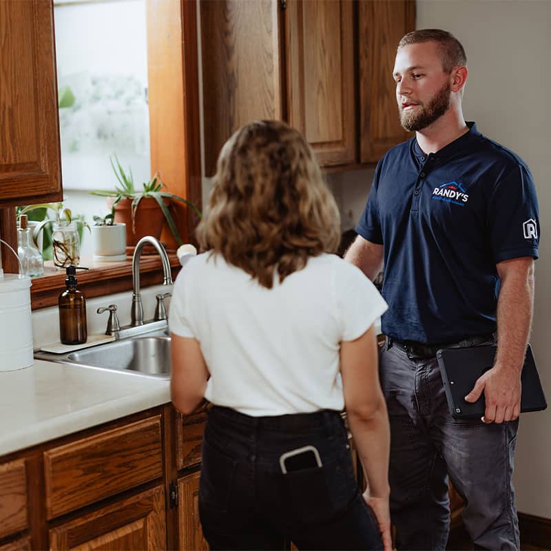 A Randy's employee discusses kitchen details with a woman near the sink.