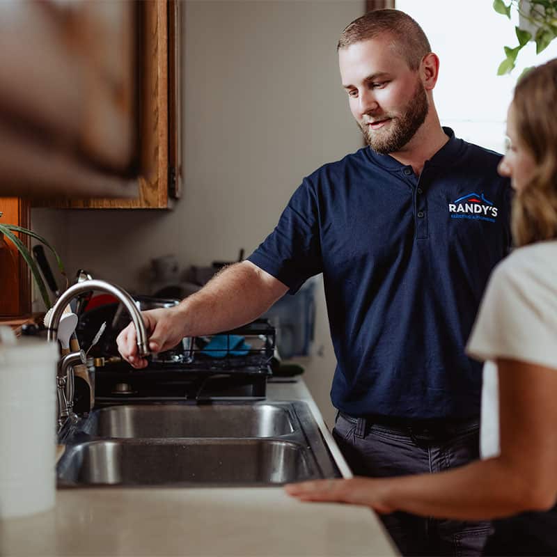 Plumber from Randy's Plumbing demonstrates a kitchen faucet to a customer.