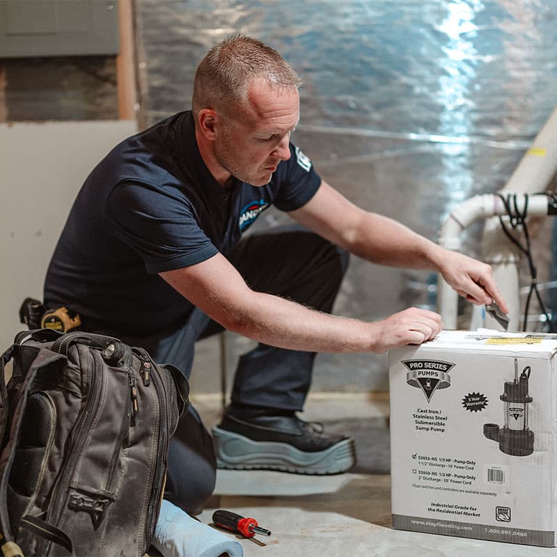 A man inspecting a Pro Series pump box in a basement setting.