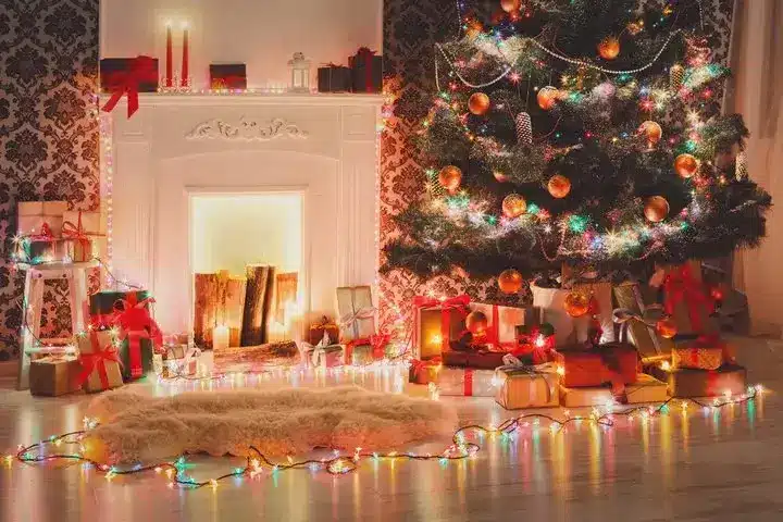 Cozy Christmas scene with decorated tree, gifts, and lit fireplace adorned with colorful lights and festive ornaments.