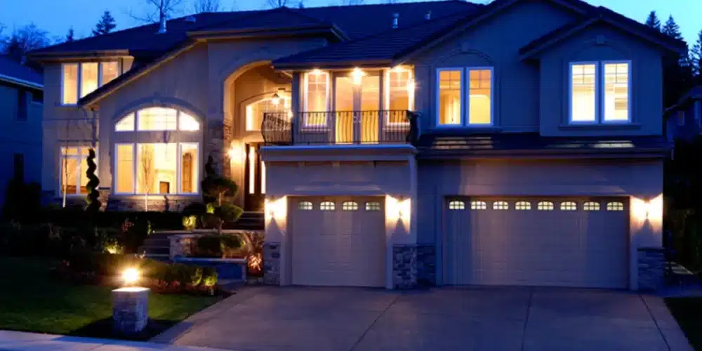 Modern two-story house illuminated at night with garage and large windows.