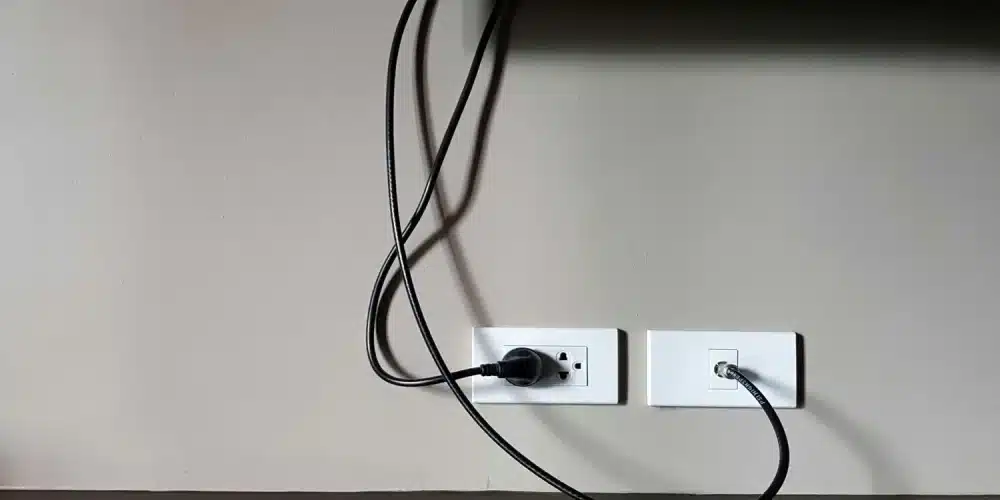 Wall-mounted TV with cables plugged into electrical and coaxial outlets.