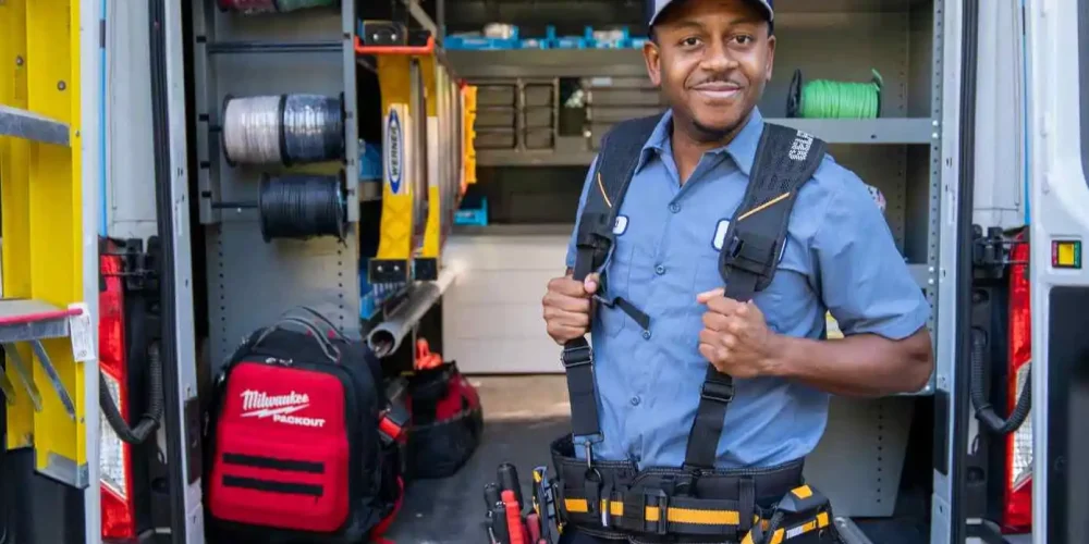 Electrician standing inside a well-organized work van filled with tools and equipment.