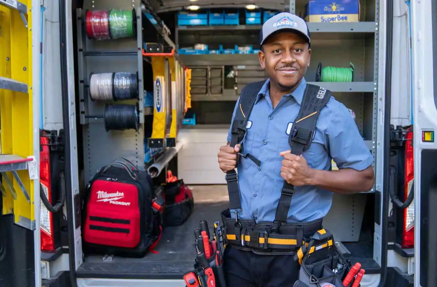 Electrician standing inside a well-organized work van filled with tools and equipment.