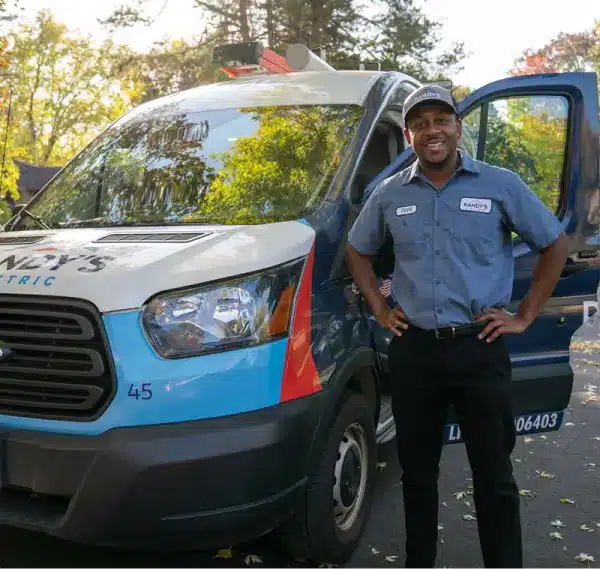 Connor standing next to Randy's Electric van with open door, wearing uniform and cap.