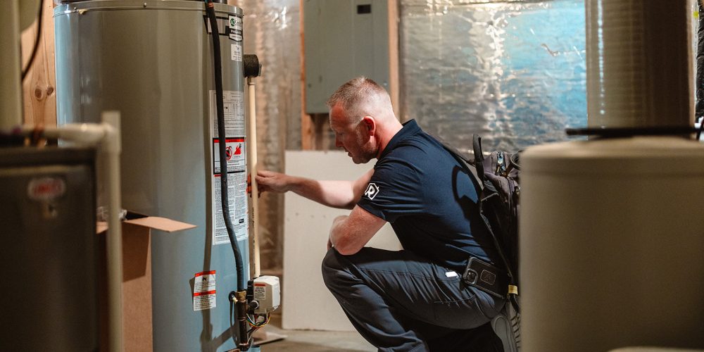 A licensed plumber from Randy’s Electric & Plumbing inspecting a water heater inside the basement of a Minnesota home.