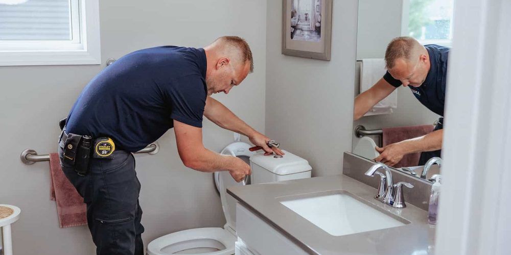A plumber from Randy’s Electric & Plumbing performing repairs on a toilet.