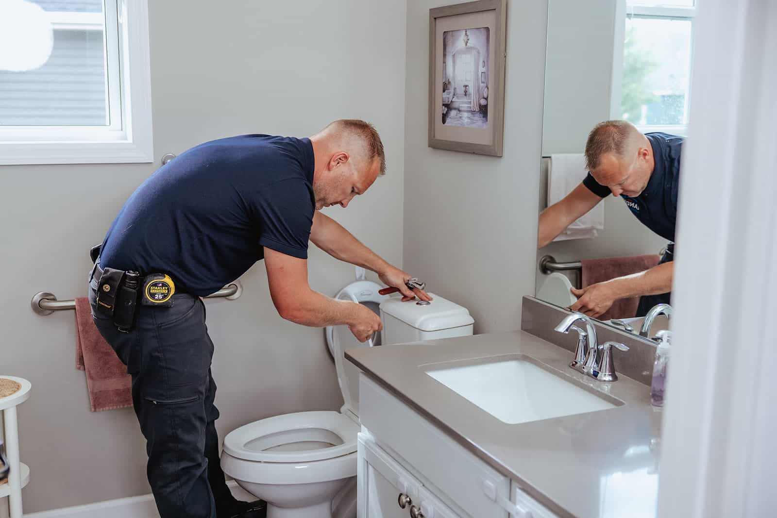 A plumber from Randy’s Electric & Plumbing performing repairs on a toilet.