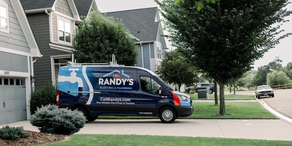 A Randy’s Electrical & Plumbing van parked outside of a suburban home.