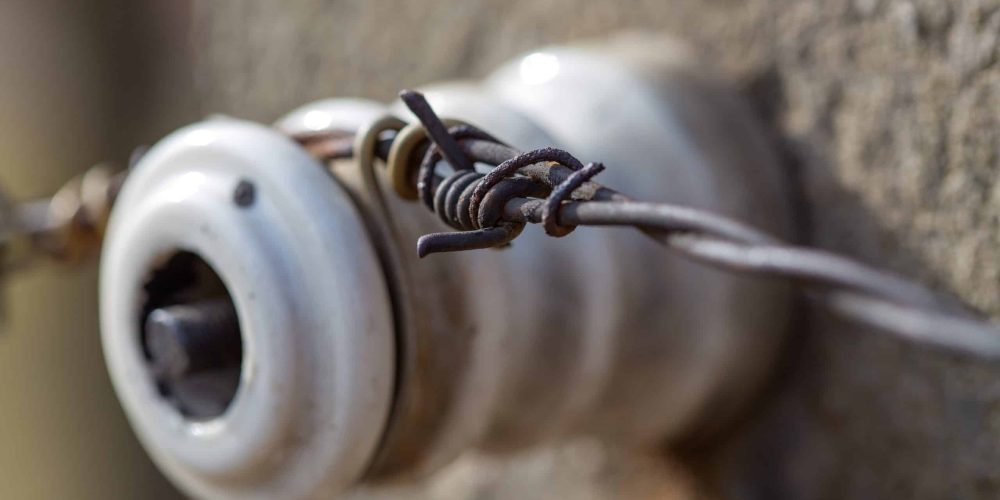 A closeup of old knob & tube wiring in a Minnesota home with a porcelain electrical insulator.