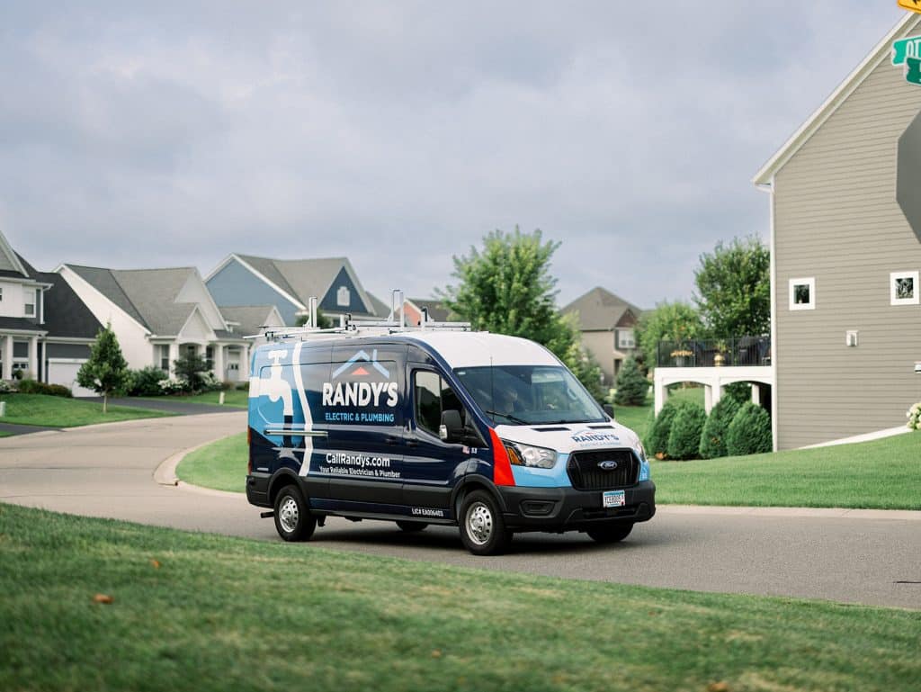 Randy's Electric & Plumbing service van driving through a suburban neighborhood street